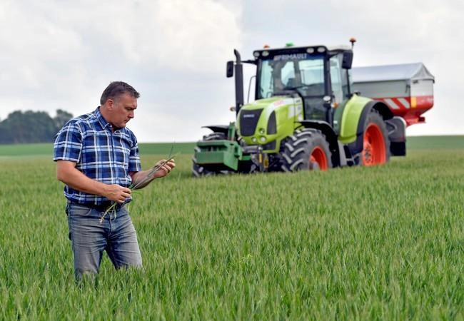 Un agriculteur dans un champ devant son tracteur